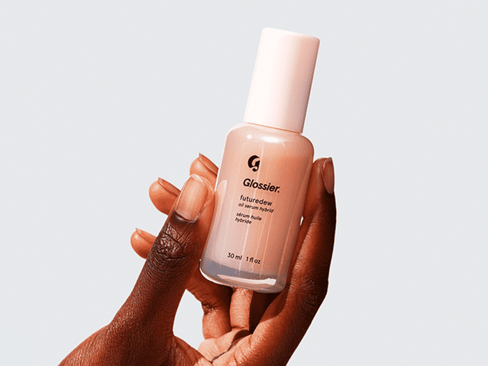 Botol serum Glossier Futuredew berwarna peachy-glow dengan pump aplikator, cocok untuk menciptakan tampilan kulit dewy dan sehat alami. Serum oil hybrid ini memberi efek glass skin instan tanpa rasa lengket, ideal untuk kulit tropis di Indonesia.