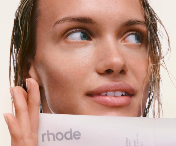 Seorang wanita memegang Rhode Pineapple Refresh Cleanser dengan kemasan kuning pastel