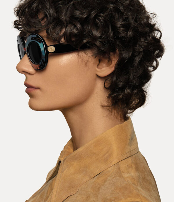 Model mengenakan Vivienne Westwood Sunday Sunglasses tampak samping dengan desain bingkai ikonik